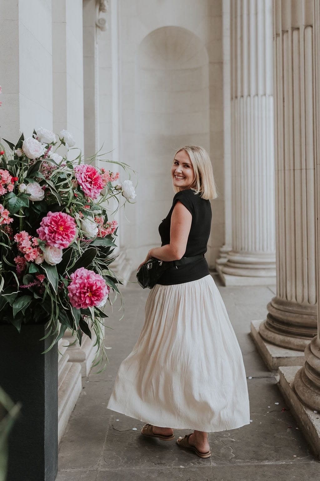 Bride with her florals beside a stone column