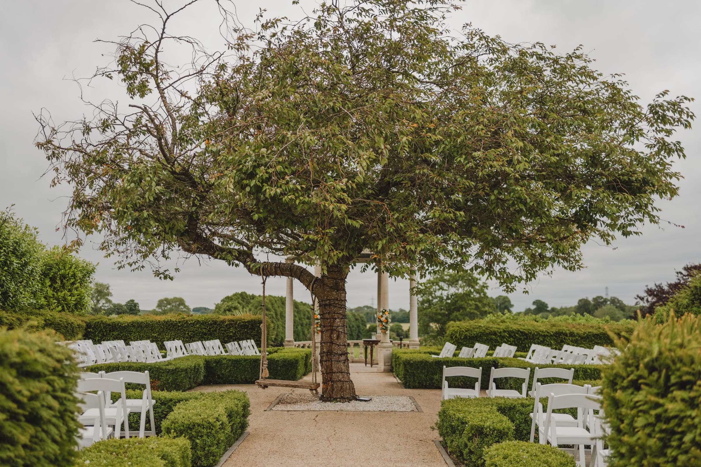 An outdoor ceremony set beneath a tree in the garden